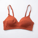 A terracotta orange wireless bra with wide adjustable shoulder straps, laid flat against a clean white background.