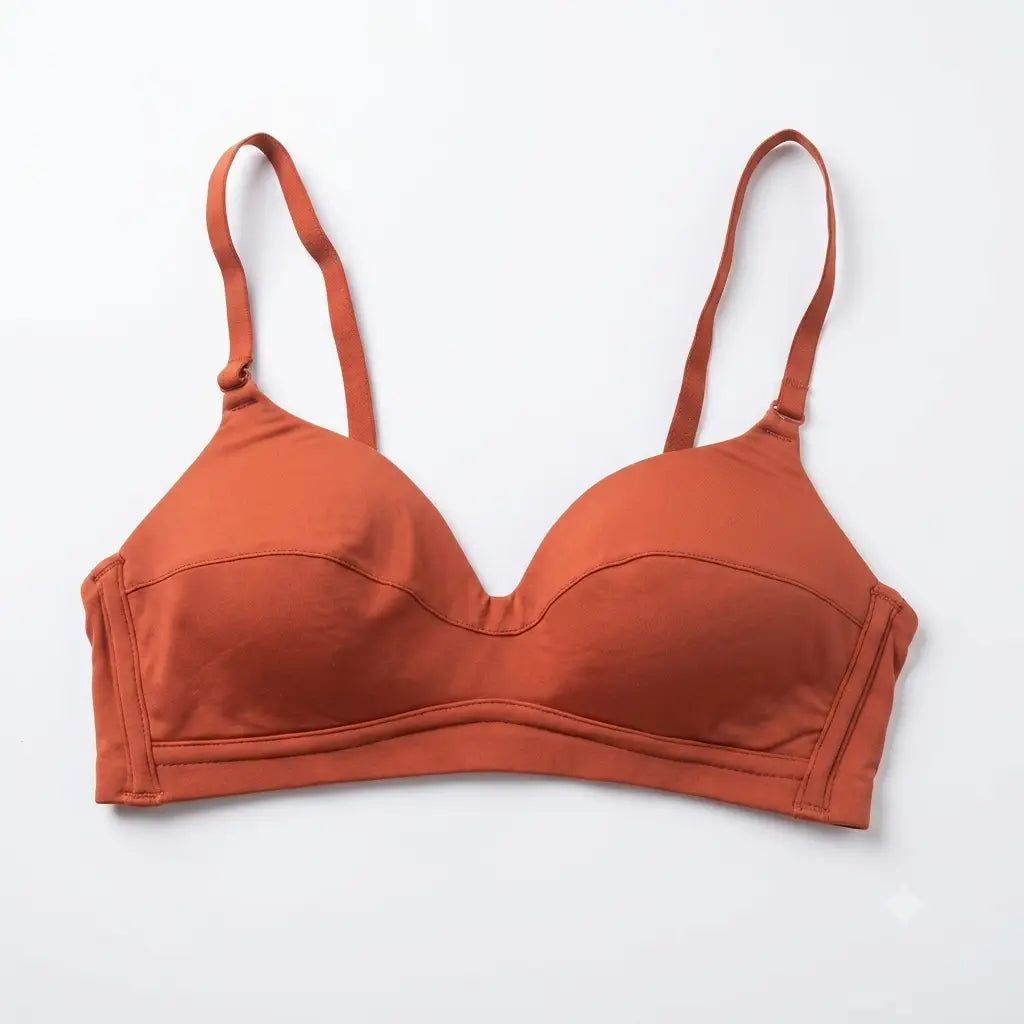 A terracotta orange wireless bra with wide adjustable shoulder straps, laid flat against a clean white background.