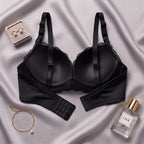Black lace-trimmed underwire bra laid flat on a silver satin fabric background, styled with a small jewelry box, earrings, bracelet, and a perfume bottle labeled LACE.