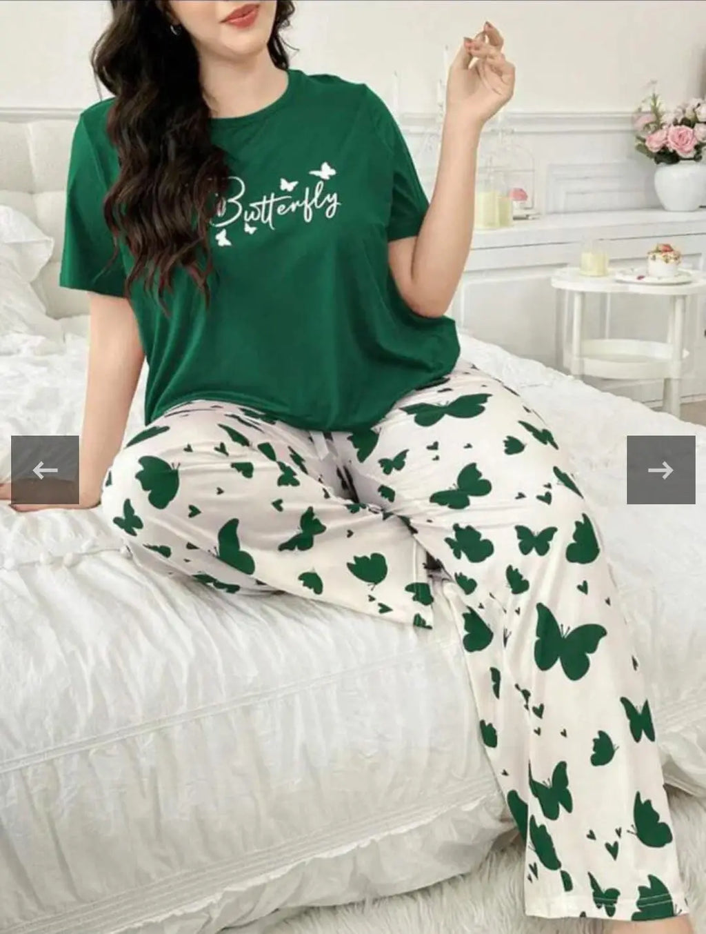 Person wearing a green t-shirt with 'Butterfly' text and white pants with green butterfly patterns, sitting on a bed.