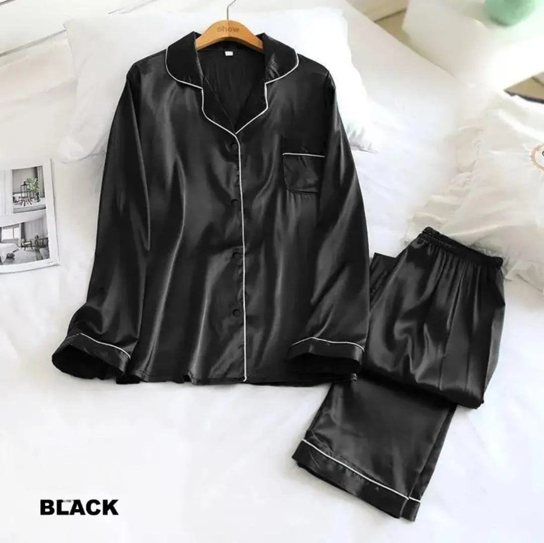 Black satin pajama set on a white bed