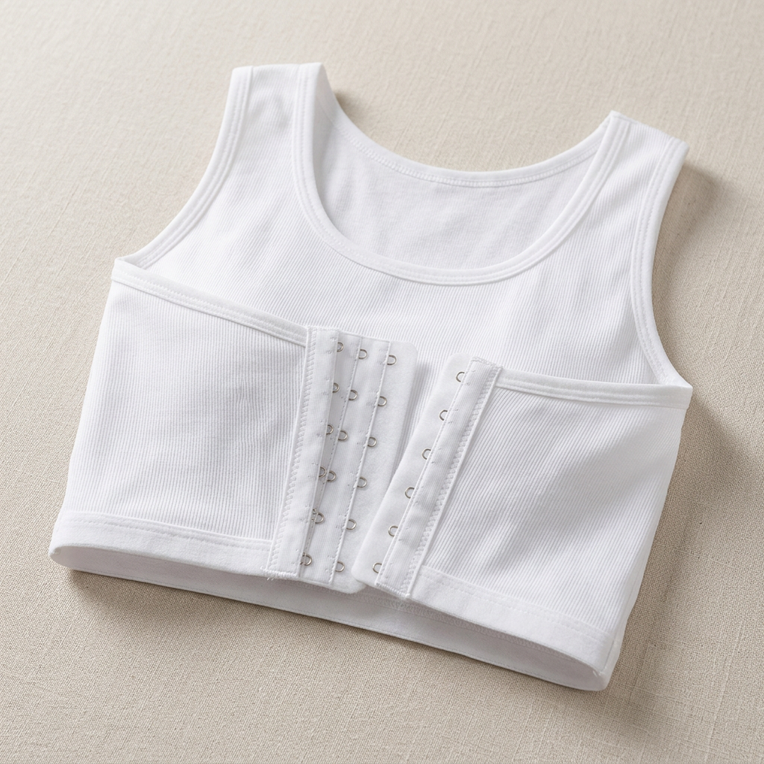 A white ribbed tank top with a built-in underwire bra cup and front hook-and-eye closure, laid flat on a textured beige background.
