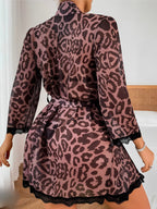 A woman wearing a pink leopard-print robe with black lace trim, shown from the back in a bedroom setting.